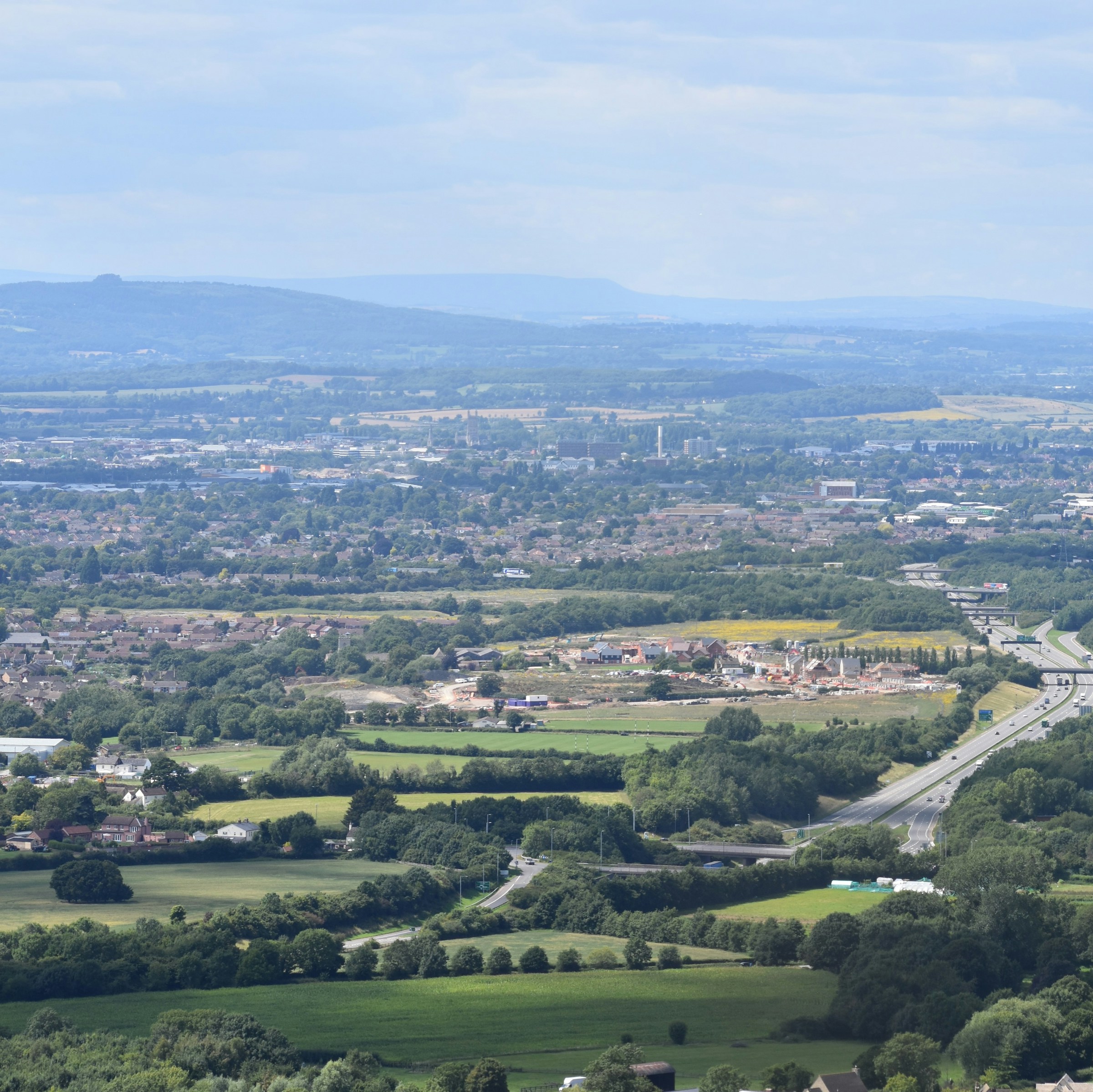A green pastoral landscape near the Cotswold ridge, viewed from above.